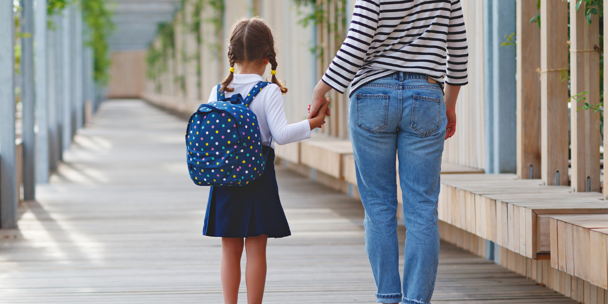 Parent holding child's hand outside school